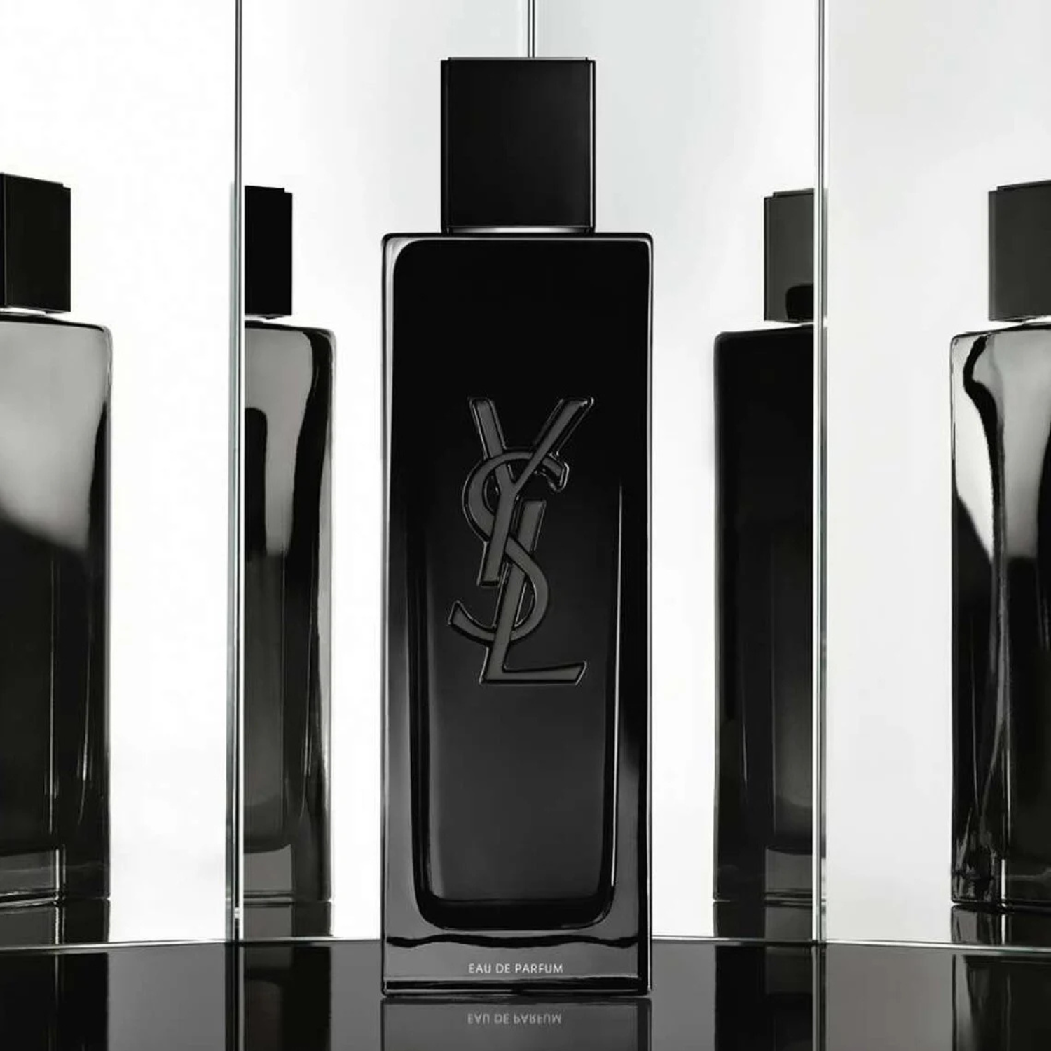 Black YSL perfume bottle on a reflective surface with a white background