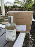 Bottle of Sandalwood 53 perfume by Maison G on a wooden surface with a cardboard box in the background.