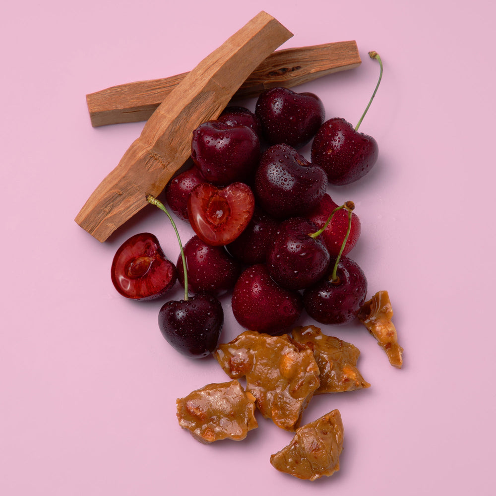 Cherries with a cinnamon stick and dried fruit on a pink background