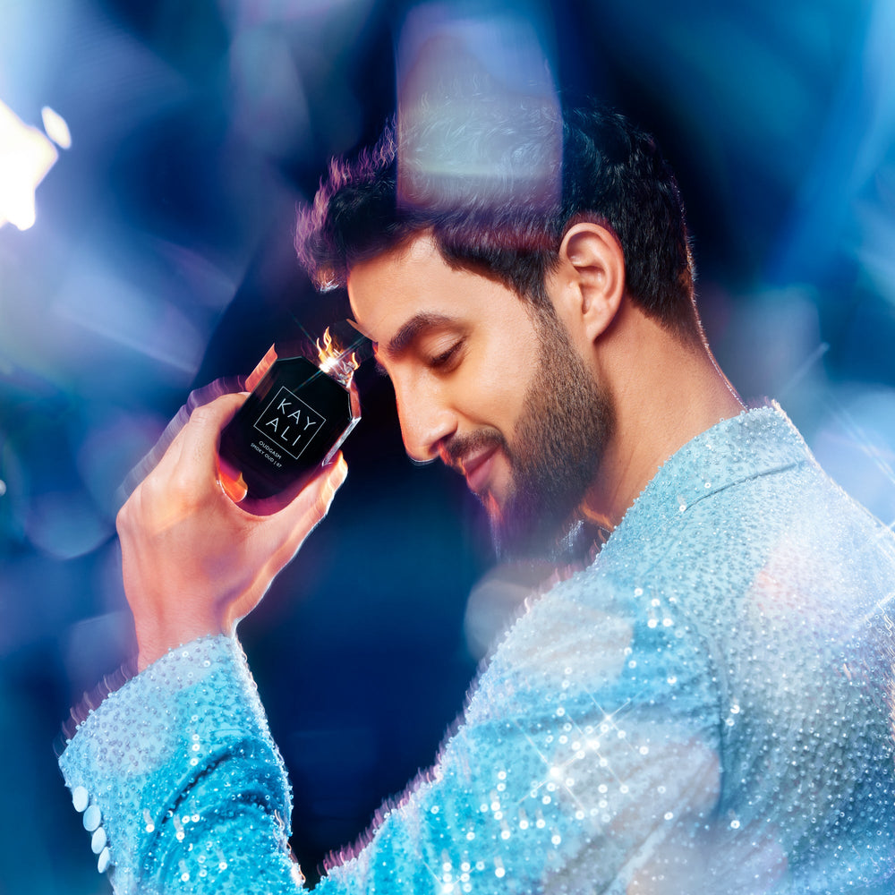 Man holding a black box with a sparkler against a blue and purple gradient background