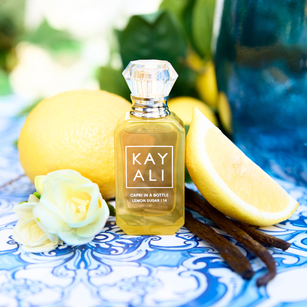 Perfume bottle labeled 'KAY ALI' with lemons, a rose, and vanilla beans on a decorative plate.