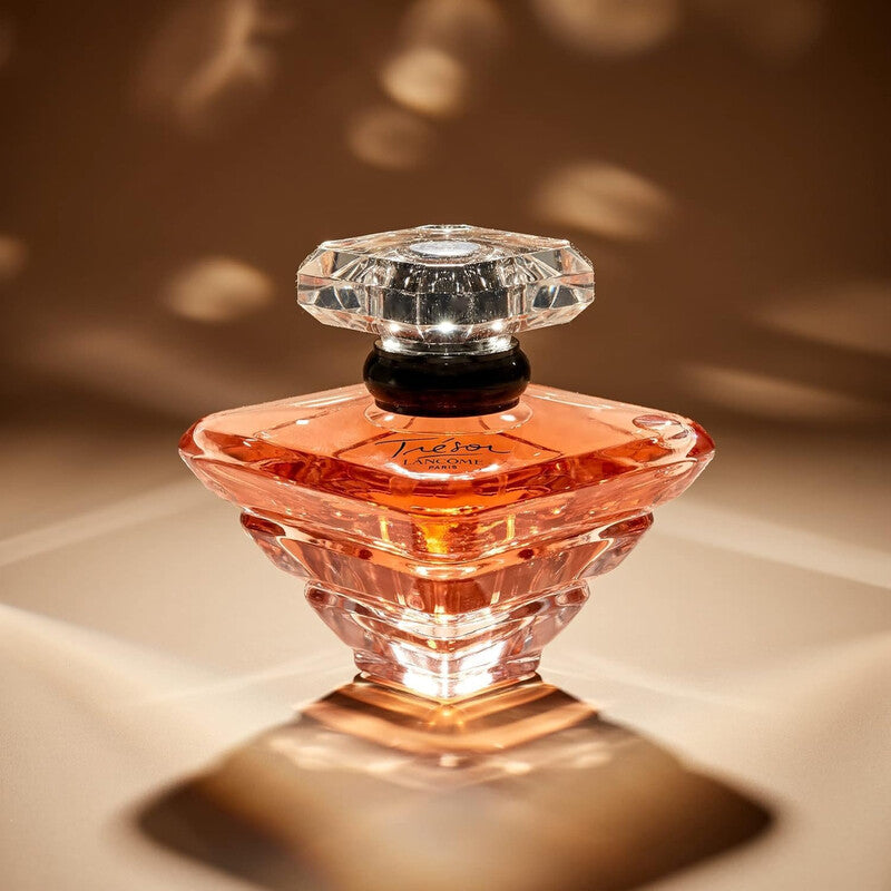 Perfume bottle with a clear crystal cap on a reflective surface