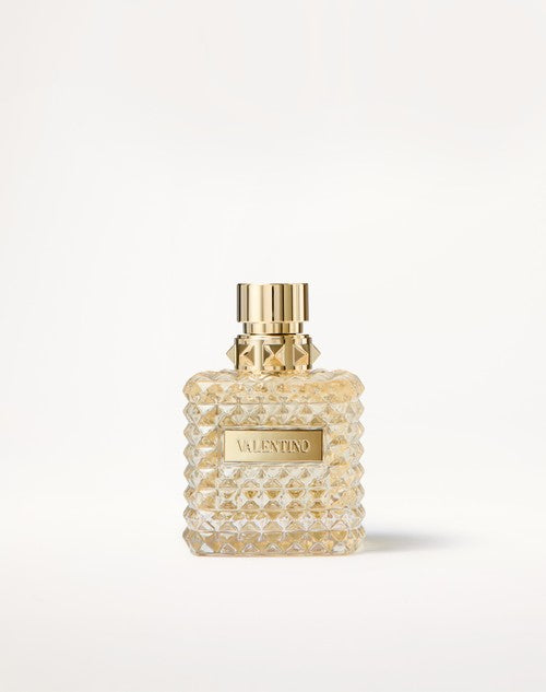 Perfume bottle with gold cap and textured design on a white background