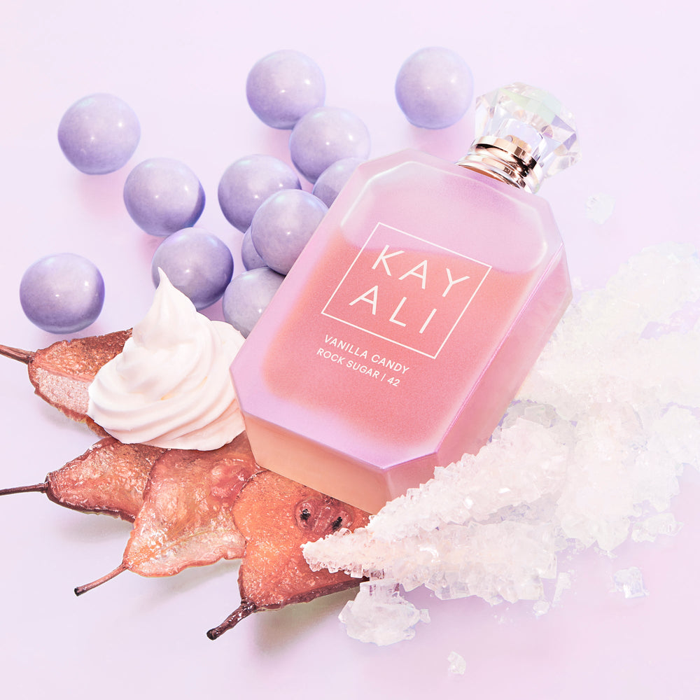 Pink KAYALI perfume bottle with grapes and pears on a light purple background