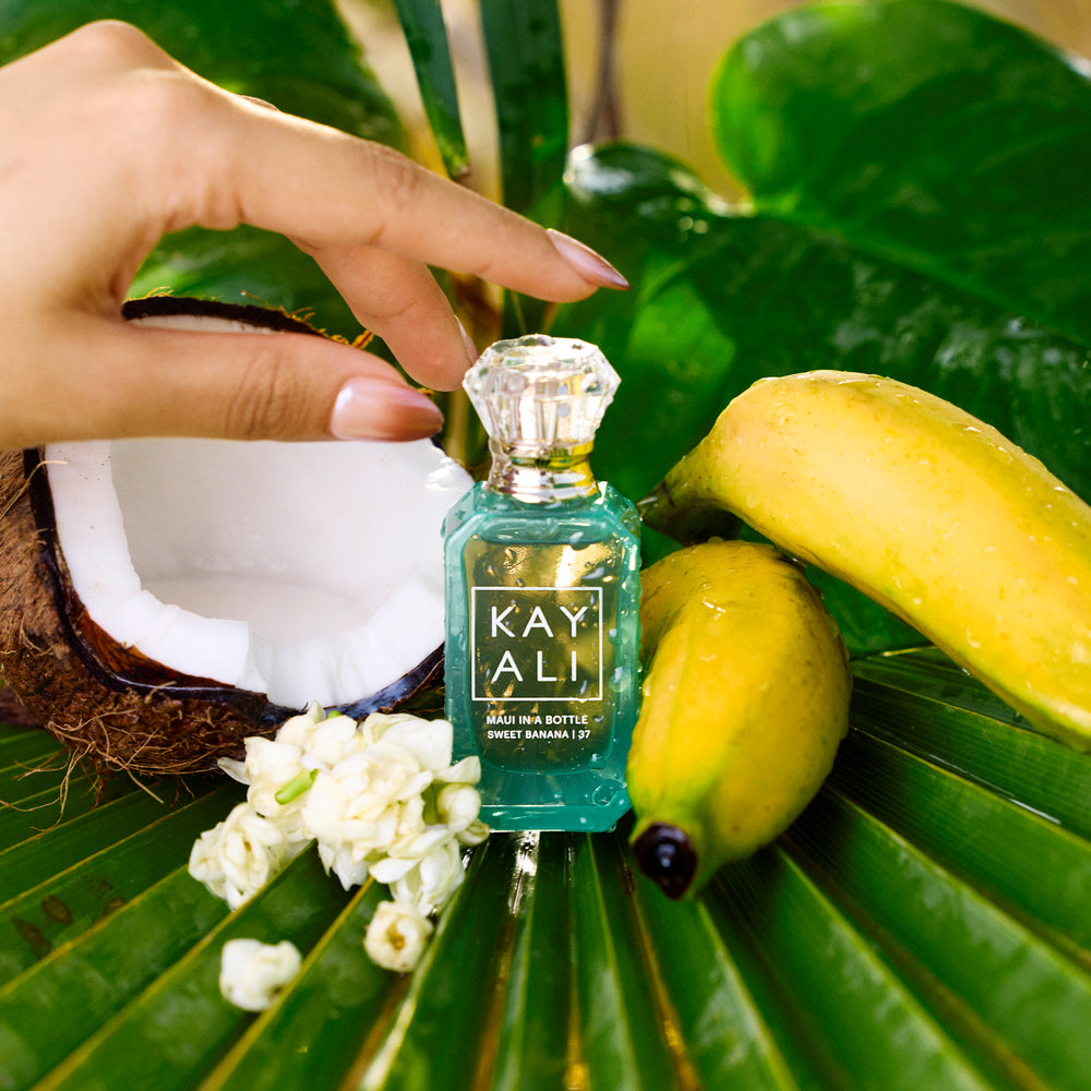 Small bottle of KAY ALI perfume on a leaf with bananas and flowers