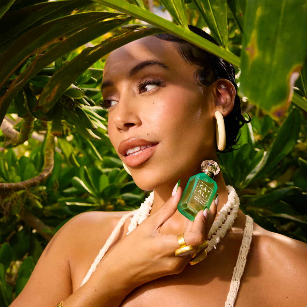 Woman holding a green bottle with a tropical background