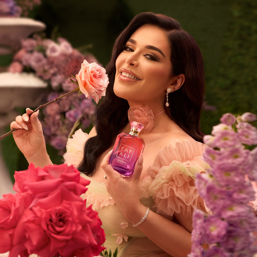 Woman holding a pink rose and a perfume bottle with floral background